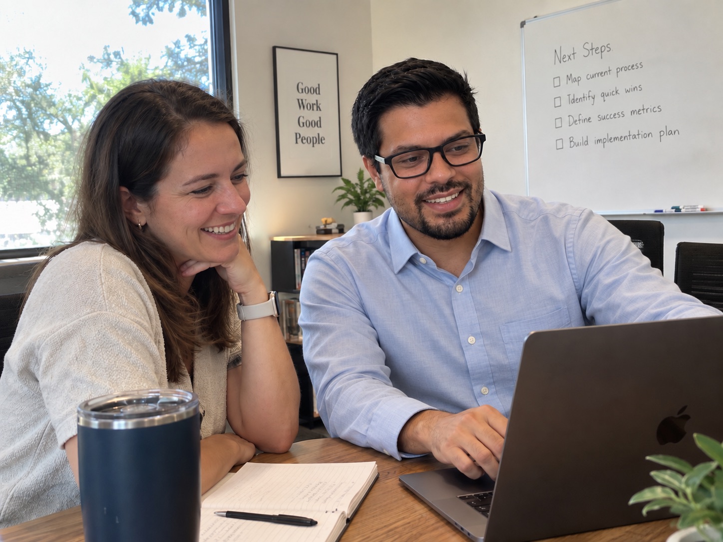 Two business owners review work together on a laptop at a conference table